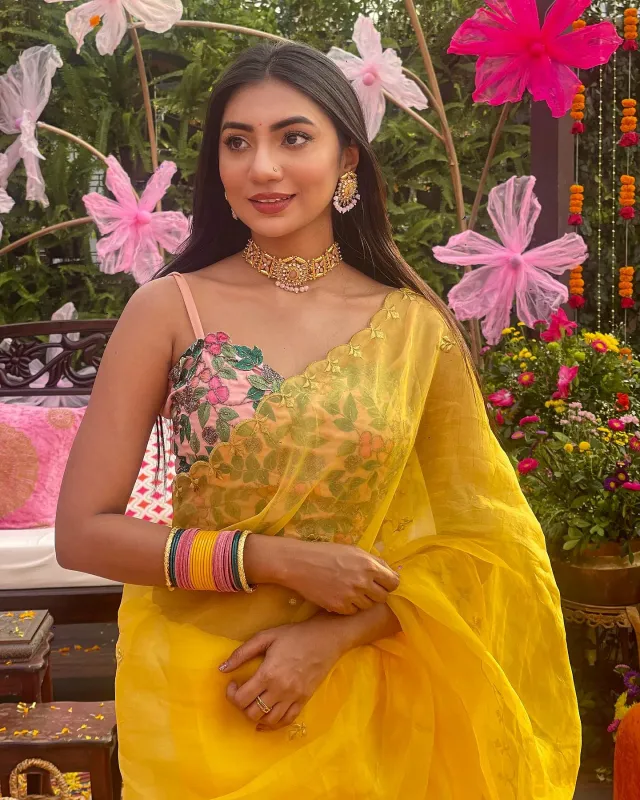 বাসন্তী জর্জেট শাড়ির সাথে ফুলেল এমব্রয়ডারির গোলাপি স্লিভলেস স্টেটমেন্ট ব্লাউজ পরেছেন সুনেরাহ।