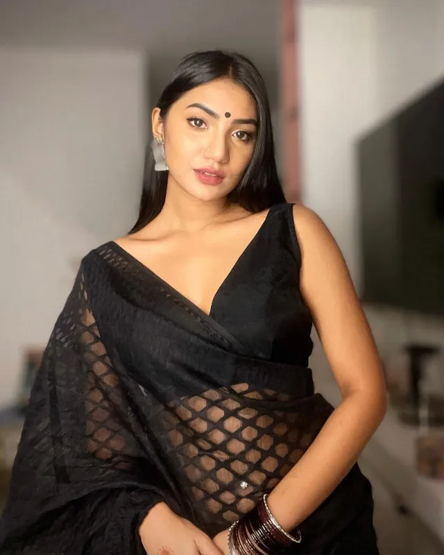 কালো শিয়ার ফেব্রিকের চেকার্ড শাড়ির সাথে ডিপনেক কালো স্লিভলেস সিল্কের ব্লাউজ পরেছেন তিনি।