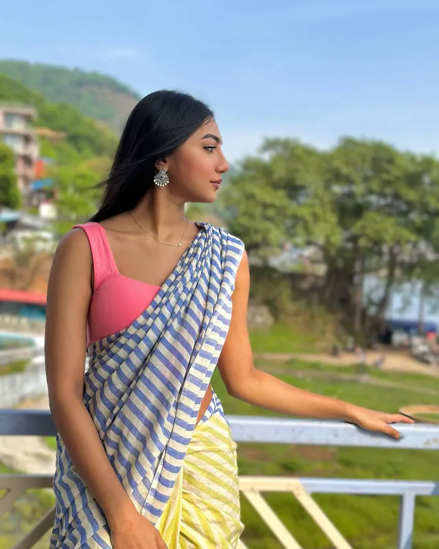 নীল-হলুদ ডোরাকাটা সাদা শাড়ির সাথে কন্ট্র্যাস্ট গোলাপি স্লিভলেস ব্লাউজ পরেছেন সুনেরাহ।