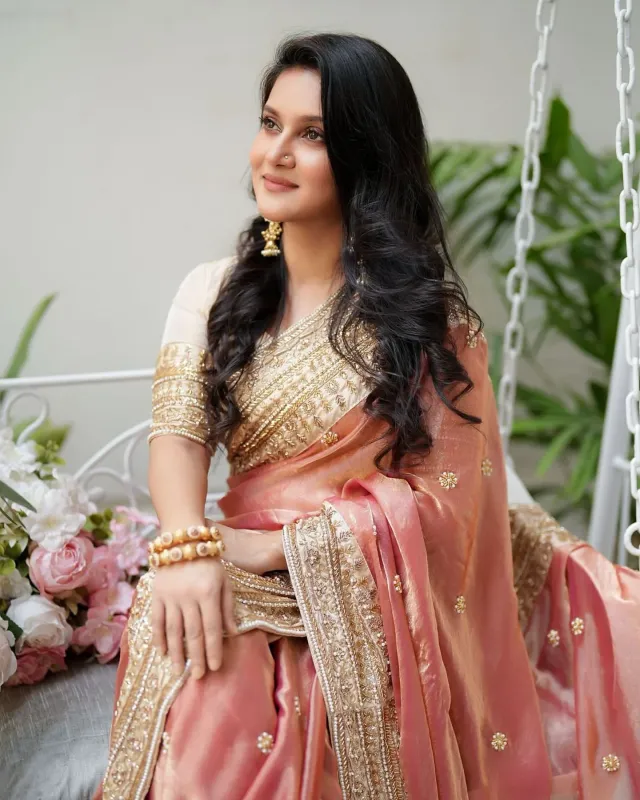 পিচরঙা শাড়ির সোনালি পাড় ও আঁচল মিথিলার সাজে এনেছে গর্জিয়াস ভাব। হাতে ও কানে সোনালি গয়না।